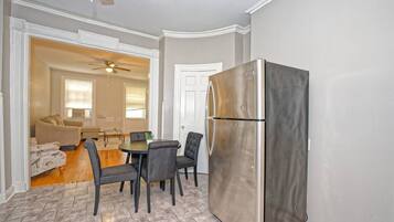 A compact living space with a dining area, a kitchenette, and a ceiling fan.