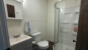 Casa de banho com sanita, lavatório e cabine de duche em vidro.