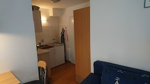 A compact living space with a kitchenette, a dining area, and a sofa.