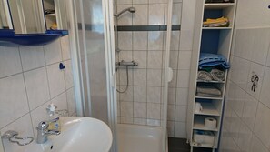 Ein Badezimmer mit Waschbecken, Spiegel, Dusche und Handtuchhalter.