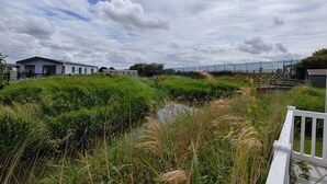 A riverside view with a white building, a wooden deck, and a metal fence. - Marine Holiday Park - 21nc (Rhyl)