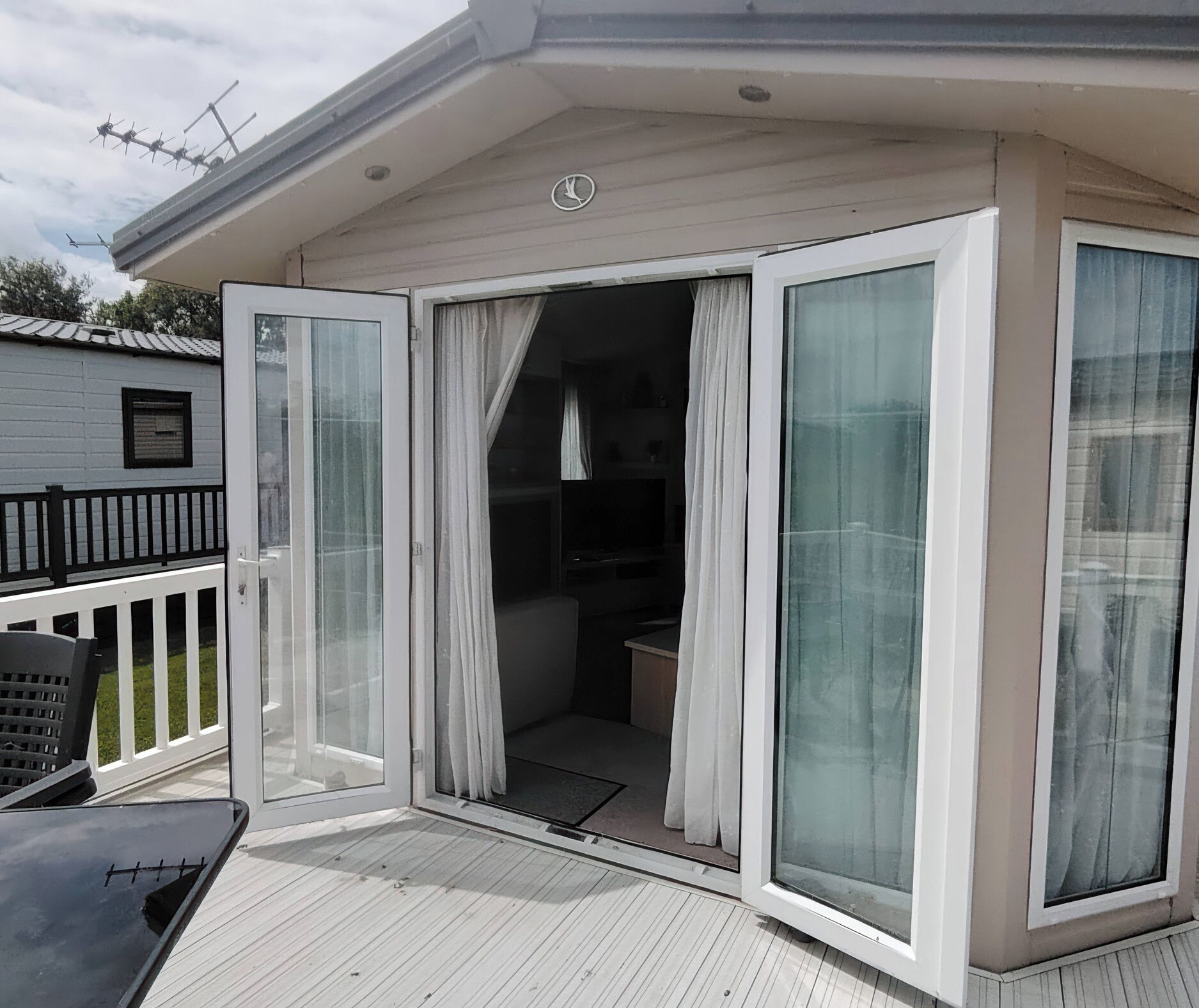 A room with a sliding glass door leading to a balcony, a small seating area, and a visible TV.