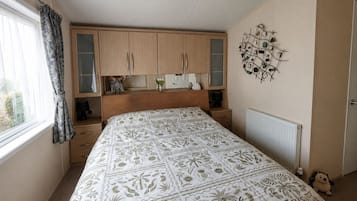 Un dormitorio con cama, armarios de madera, un radiador y un elemento decorativo en la pared.