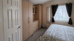 A bedroom with a bed, wardrobe, and a mirror. - Marine Holiday Park - 21nc (Rhyl)