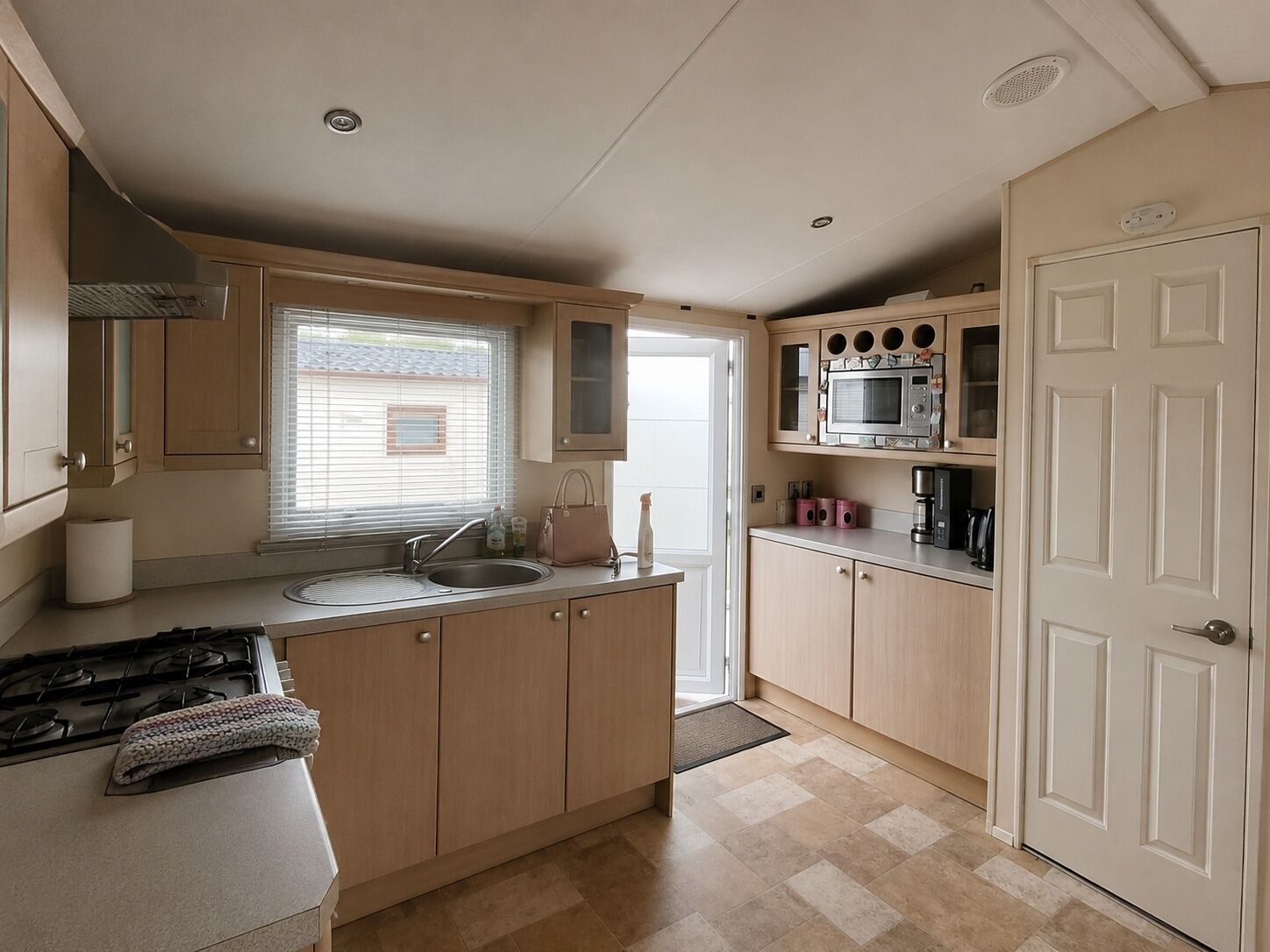A compact kitchen with a gas stove, a sink, a microwave, and wooden cabinets.