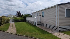 A mobile home with a front porch, a small staircase, and a paved driveway. - Marine Holiday Park - 21nc (Rhyl)