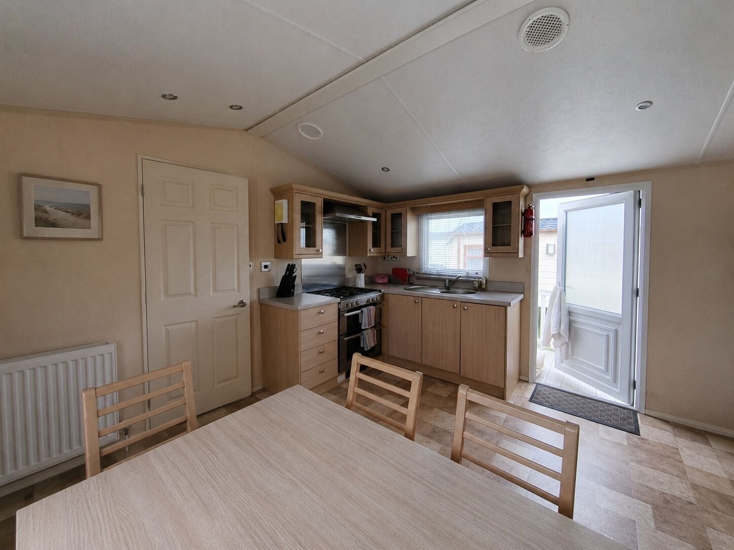 A compact kitchen with a dining table, chairs, a stove, and a sink.