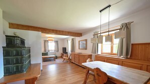 A spacious room with a wooden dining table, benches, a green cabinet, and a window with curtains. - Alpenvilla Liboria Wallgau: 220-square-meter vacation home with hobby room (Wallgau)