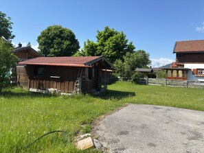 Entorn rural amb edificis de fusta, un camí de grava i un prat.