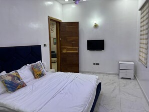 Een slaapkamer met een bed, een televisie, een nachtkastje en een deur.