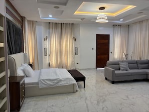 Una habitación de hotel moderna con una cama, sofá y una puerta de madera.