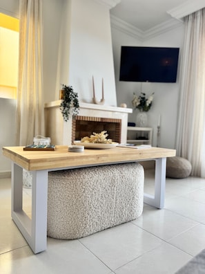 Ein modernes Wohnzimmer mit Couchtisch aus Holz, Kamin und einem an der Wand befestigten Flachbildfernseher.