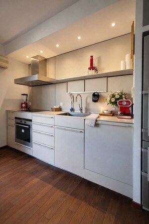 A modern kitchen with a built-in oven, a sink, and a stove. - Vercors Festivals next to the sea & beach (Cannes)