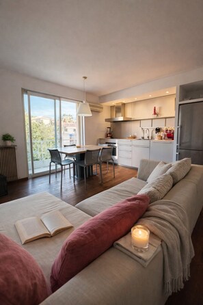 A modern living room with a sofa, a dining area, and a kitchen. - Vercors Festivals next to the sea & beach (Cannes)
