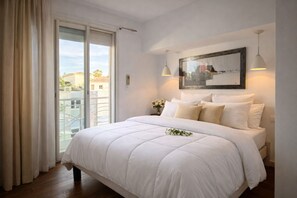 A bedroom with a large bed, a sliding glass door to a balcony, a framed picture on the wall, and a pendant light. - Vercors Festivals next to the sea & beach (Cannes)