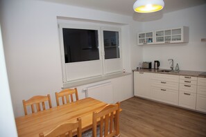 A kitchen with a dining table, chairs, cabinets, and a window. - Apartment Joanna – 70 m² of comfort on Lake Turawa in Szczedrzyk, Poland (Upper Silesia) (Szczedrzyk)