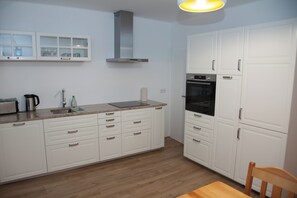 A modern kitchen with white cabinets, a stainless steel range hood, and a built-in oven. - Apartment Joanna – 70 m² of comfort on Lake Turawa in Szczedrzyk, Poland (Upper Silesia) (Szczedrzyk)