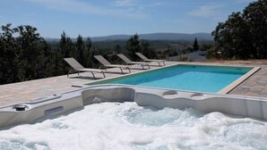 Ein Whirlpool mit Pool, Liegestühlen und Blick auf die Berge.