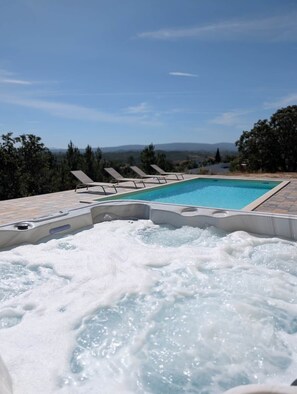 Ein Whirlpool mit Pool, Liegestühlen und Blick auf die Berge.