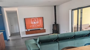 Ein modernes Wohnzimmer mit einem Ecksofa, einem Holzesstisch und einem an der Wand befestigten Fernseher.