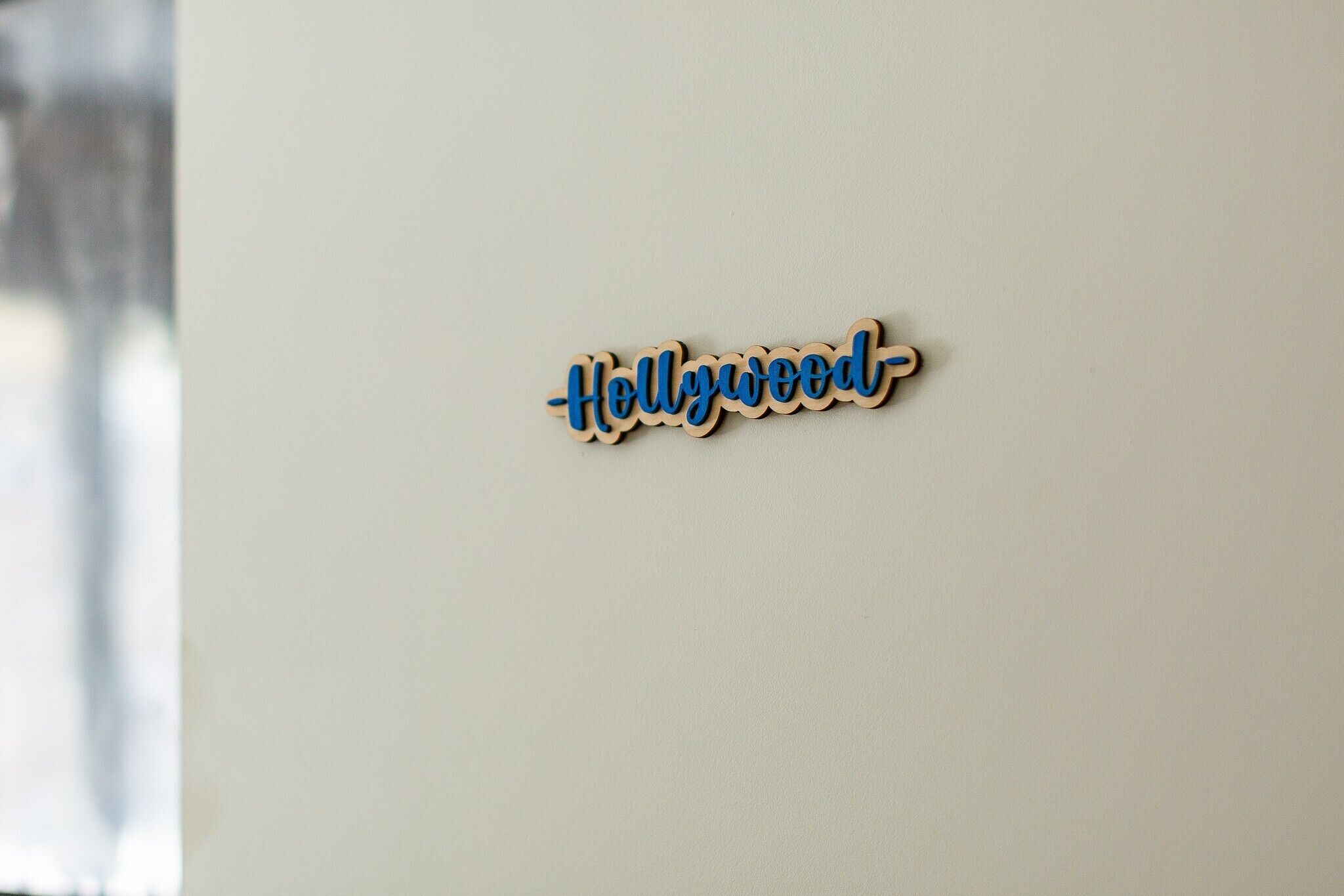 Een houten bord met de tekst 'Hollywood-' op een muur.