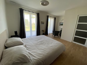 Quarto com uma cama grande, uma escrivaninha e uma cadeira.