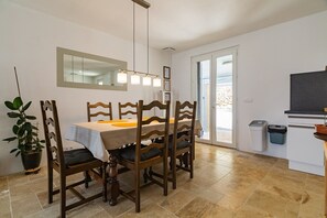 A dining area with a table, chairs, a potted plant, a mirror, and a television. - Holiday Home 'Le Beauregard - Piscine' with Mountain View, Wi-Fi and Air Conditioning (Beauregard-Baret)