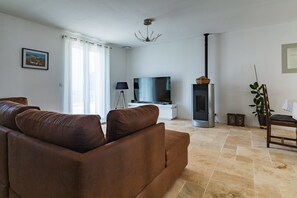 A living room with a brown sofa, a flat-screen TV, a fireplace, and a lamp. - Holiday Home 'Le Beauregard - Piscine' with Mountain View, Wi-Fi and Air Conditioning (Beauregard-Baret)