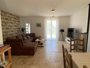 Uma sala de estar com um sofá marrom, uma mesa pequena, uma televisão e um abajur.
