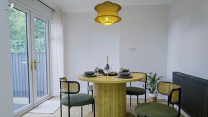 Ein Essbereich mit einem runden Tisch, vier Stühlen, einer Pendelleuchte und einem Blumentopf.