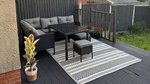 Eine Terrasse mit einer Couch, einem Couchtisch und einem Blumentopf.