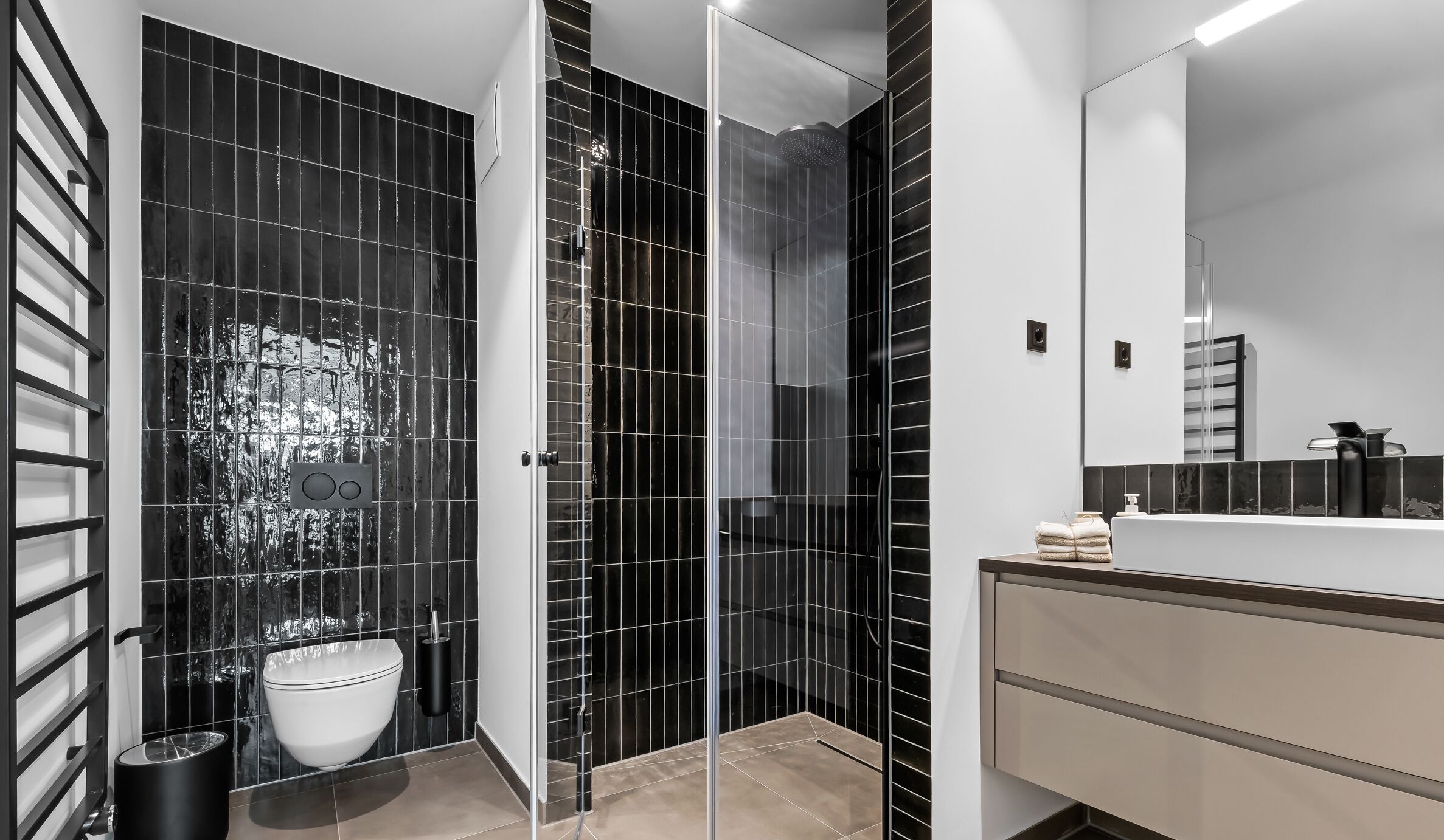 Une salle de bain moderne avec une douche à parois de verre, un lavabo blanc et un grand miroir.