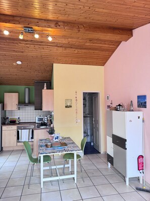 A compact kitchen with a dining area, wooden ceiling, and a white refrigerator. - Vrbo Property (Saint-Denis-d'Oléron)