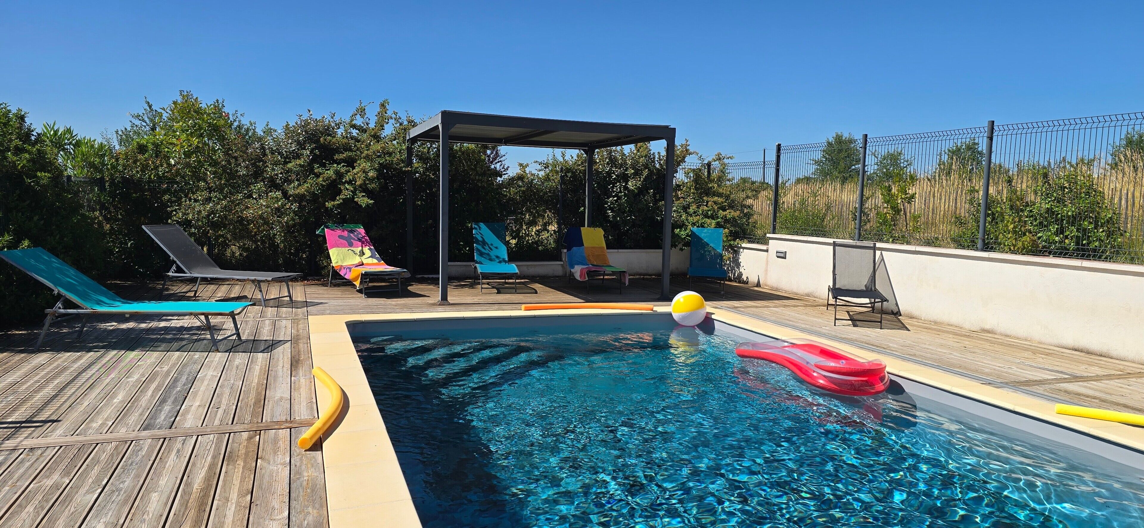 En swimmingpool med liggestole og et overdækket opholdsområde.