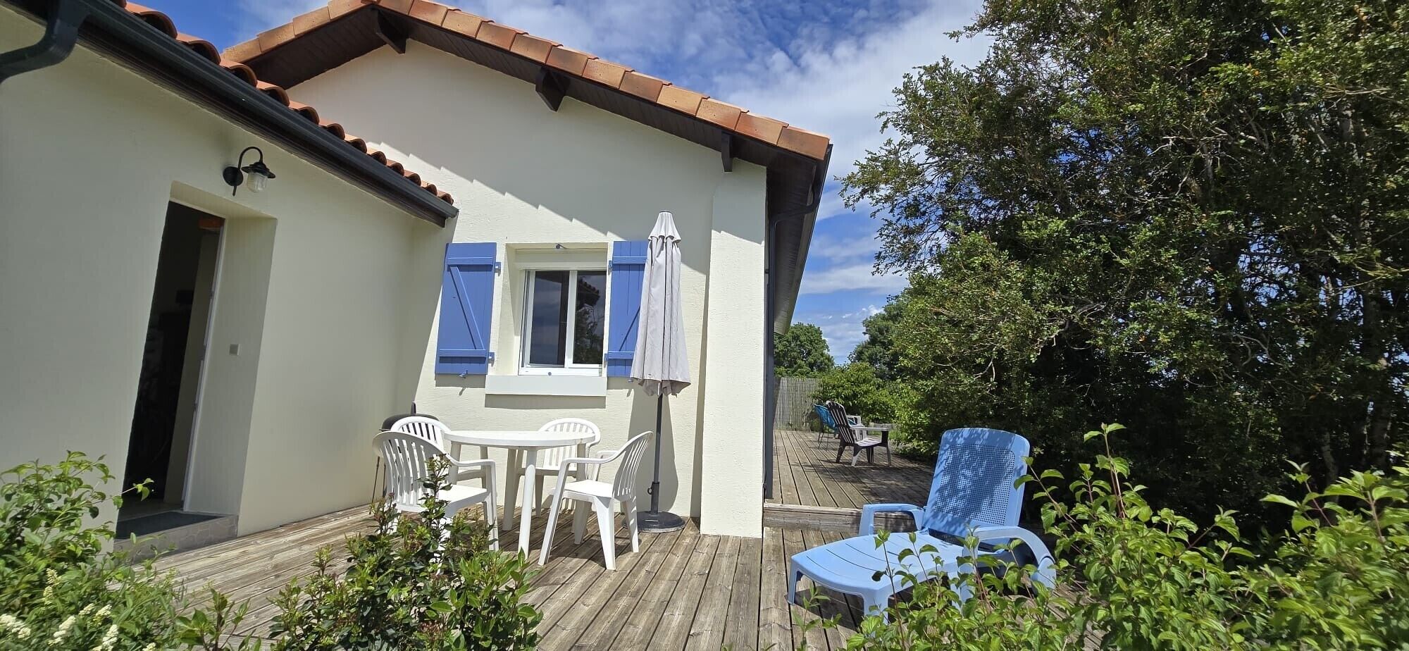 Een huis met een terras, een tafel met stoelen en een blauwe stoel.