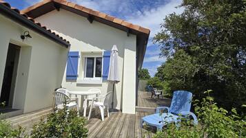 Een huis met een terras, een tafel met stoelen en een blauwe stoel.