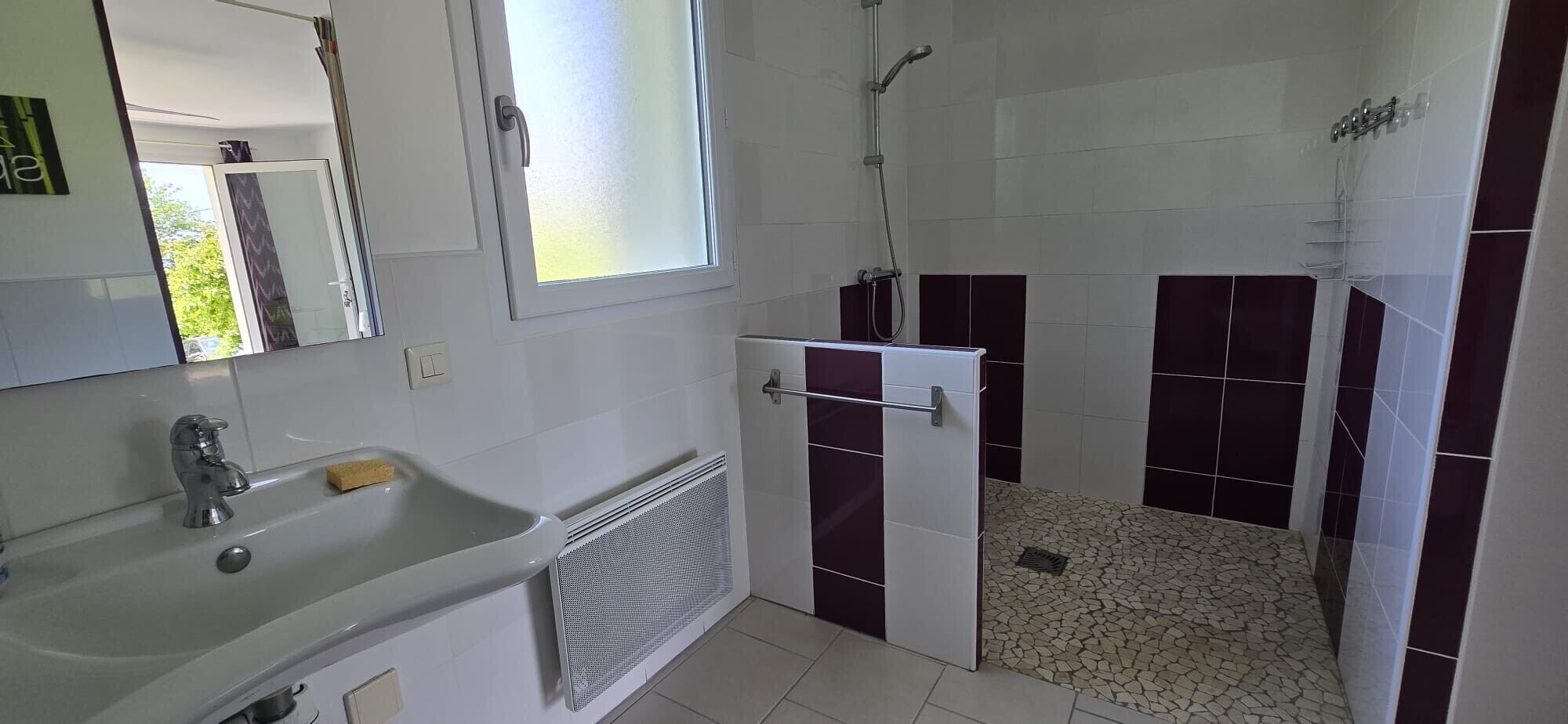 Ein Badezimmer mit Waschbecken, Spiegel, Dusche und Fliesenboden.