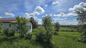 Una casa bianca con tetto rosso, circondata dal verde e sotto un cielo sereno.