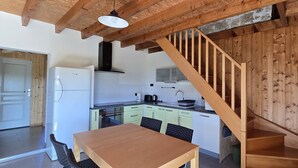Eine Küche mit Holzbalken, einer Holztreppe und einem Essbereich mit Tisch und Stühlen.