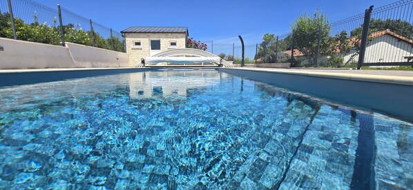 A clear swimming pool with a stone structure in the background. - Holiday Home “Gîte La Rapière En Armagnac” (Lauraët)