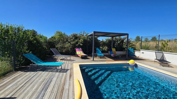 Ein Pool auf dem Dach mit Liegestühlen, einer überdachten Sitzgruppe und wolkenlosem, blauem Himmel.