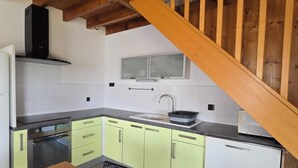 Eine Küche mit einem weißen Kühlschrank, einem Herd, einer Spüle und hellgrünen Schränken.