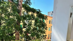 A balcony with a green metal railing, a potted plant, and a view of buildings and trees. - Apartment 2 rooms - house Martina LuxRental Apartments (Pescara)