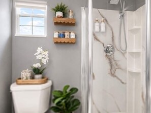 A bathroom with a shower, toilet, and shelves with toiletries. - Cozy escape | Free parking | Private Patio (Miramar)