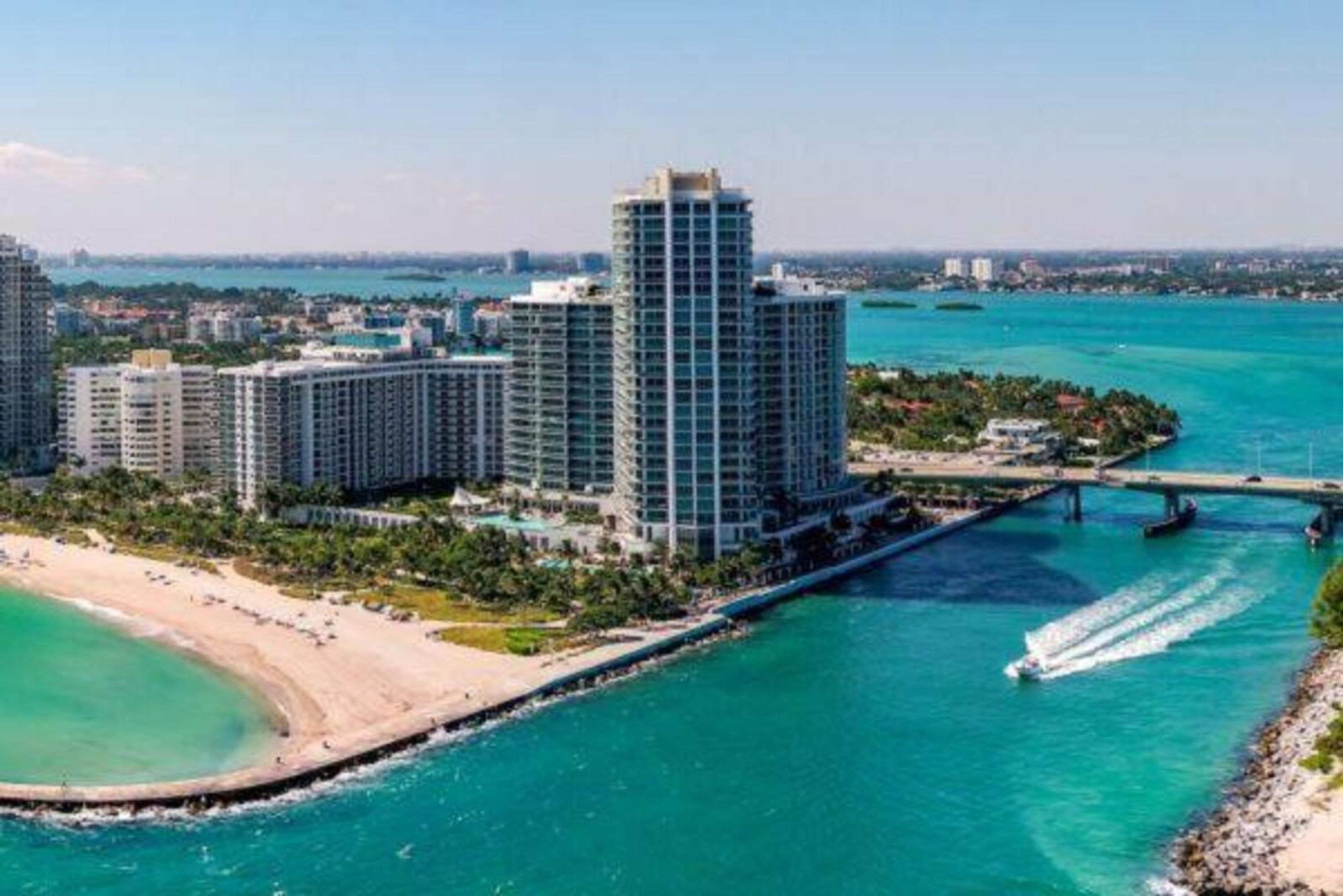 Un paisaje urbano costero con edificios altos, una playa y un puente.