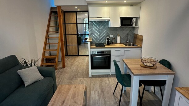 Cozinha moderna com micro-ondas embutido, forno e mesa de jantar de madeira com cadeiras.