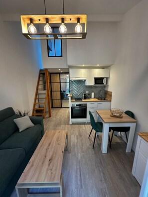 Una cocina moderna con microondas integrado, horno y una mesa de comedor de madera con sillas.