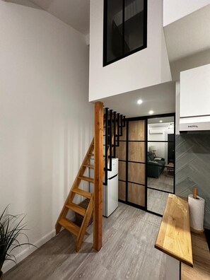 Una cocina moderna con una escalera de madera, un refrigerador blanco y una mesa de madera.