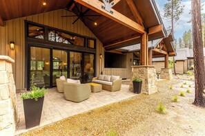 Ein überdachter Außenbereich mit Korbmöbeln, Steinpfeilern und einem Kiesweg.