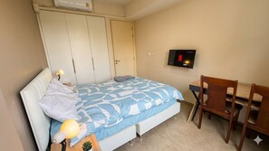 Une chambre à coucher comprenant un lit, un bureau, une chaise, une télévision et une armoire.